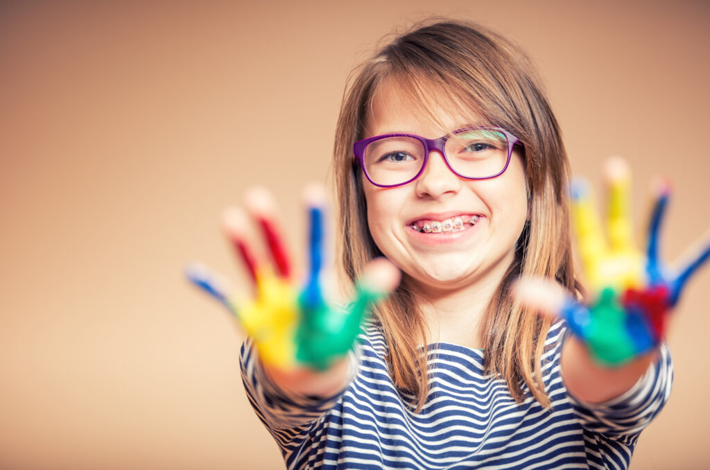 PortraitOfALittlePre-teenStudentGirlShowingPaintedHands - North Sydney Orthodontics